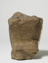 Fragment van een beeldje van een gehurkte man, met inscriptie