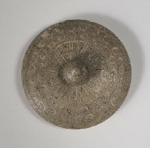 Deksel van een vaas, versierd met kleine dubbele cirkels en gegraveerde lijnen